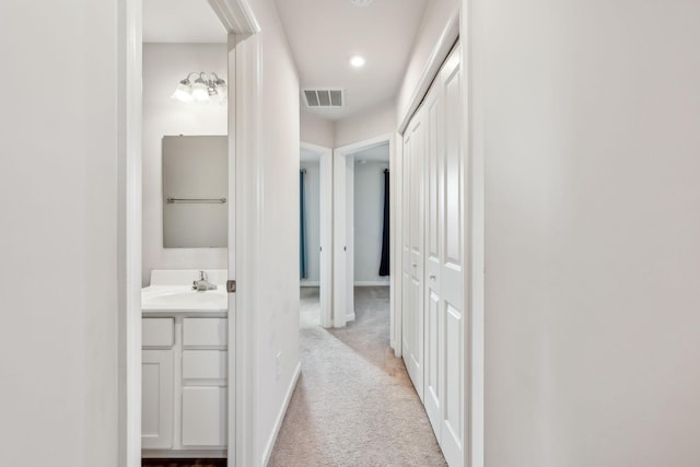 hall with light colored carpet and sink