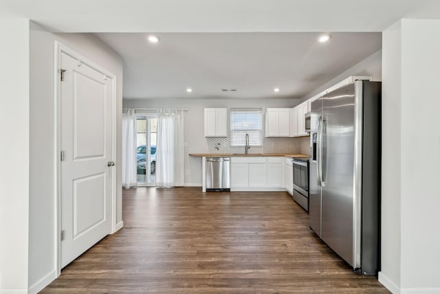 kitchen with dark wood-type flooring, sink, tasteful backsplash, appliances with stainless steel finishes, and white cabinets