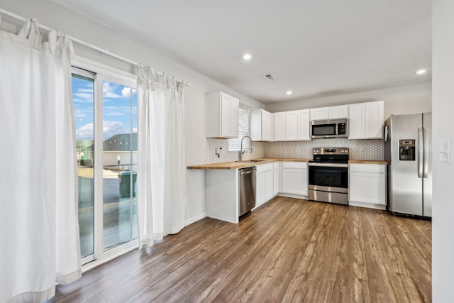 kitchen featuring appliances with stainless steel finishes, sink, white cabinets, and light hardwood / wood-style floors