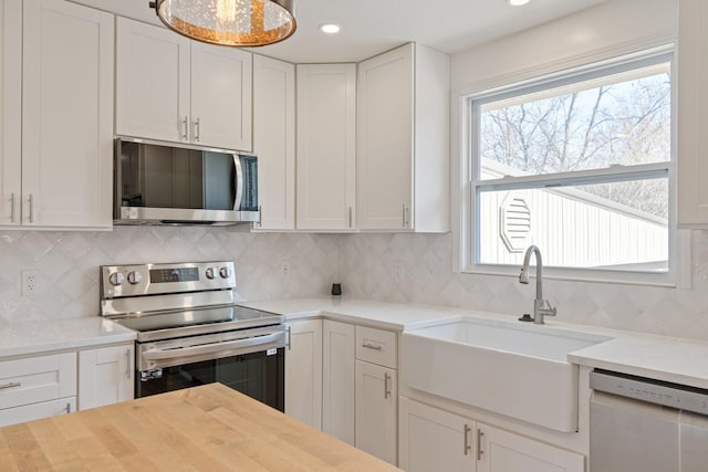 kitchen with tasteful backsplash, appliances with stainless steel finishes, sink, and white cabinets