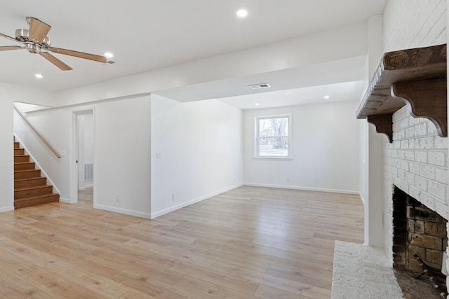 unfurnished living room featuring ceiling fan, a brick fireplace, and light hardwood / wood-style flooring