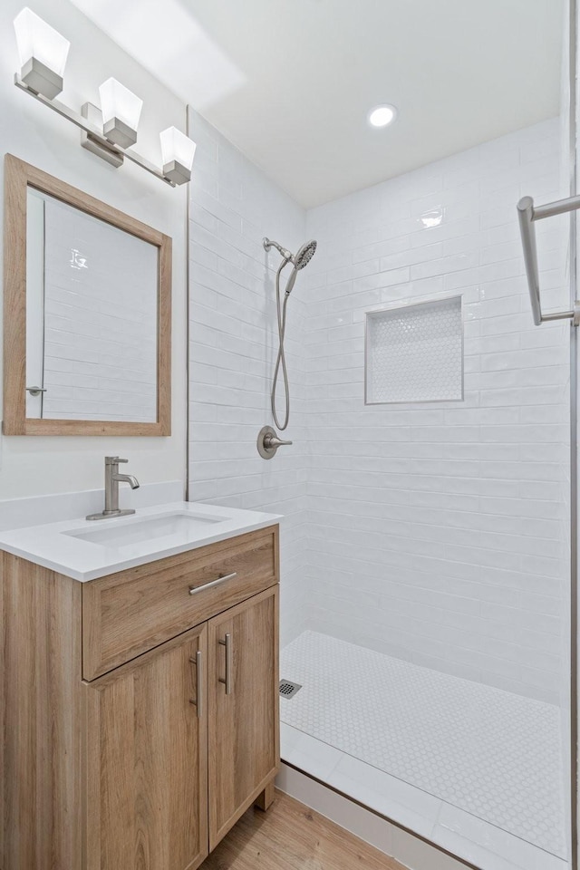 bathroom with vanity, hardwood / wood-style flooring, and a tile shower