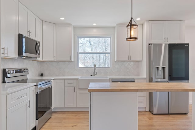 kitchen with pendant lighting, stainless steel appliances, a center island, and white cabinets