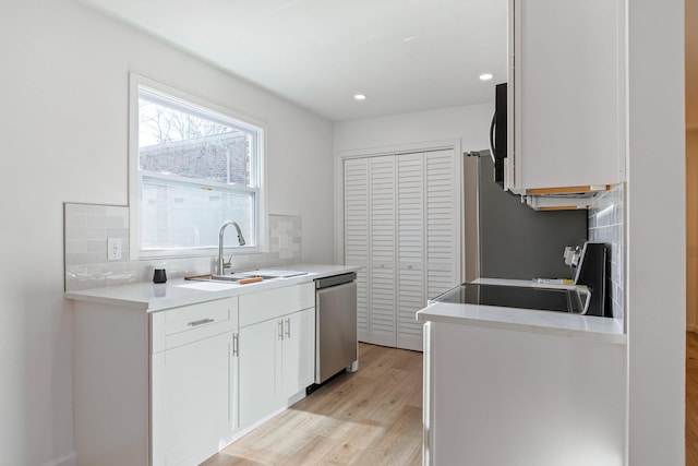 kitchen with sink, dishwasher, stove, backsplash, and white cabinets