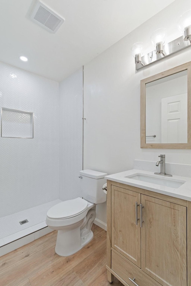 bathroom featuring vanity, wood-type flooring, toilet, and walk in shower