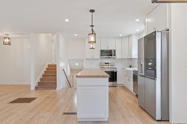 kitchen with stainless steel appliances, wooden counters, and white cabinets