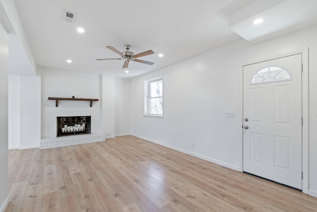 unfurnished living room featuring ceiling fan, a fireplace, and light hardwood / wood-style flooring