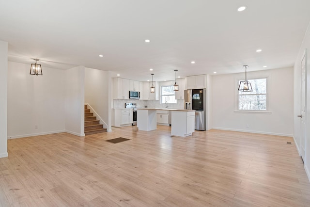 unfurnished living room with a healthy amount of sunlight, sink, and light wood-type flooring