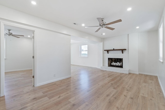 unfurnished living room featuring a brick fireplace, light hardwood / wood-style flooring, and ceiling fan