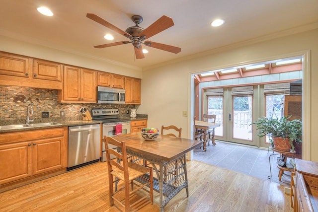 kitchen with appliances with stainless steel finishes, sink, decorative backsplash, ornamental molding, and light hardwood / wood-style floors