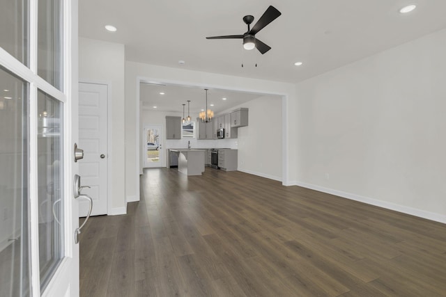 unfurnished living room with dark hardwood / wood-style floors and ceiling fan with notable chandelier