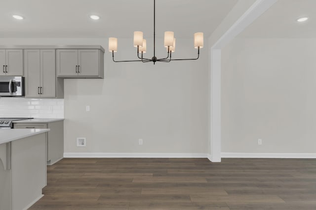 kitchen featuring gray cabinets, dark hardwood / wood-style floors, decorative light fixtures, tasteful backsplash, and an inviting chandelier