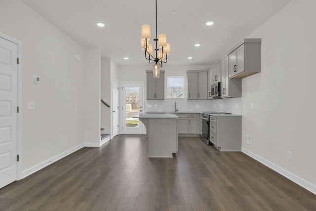 kitchen featuring dark wood-type flooring, a center island, hanging light fixtures, gray cabinets, and stainless steel appliances