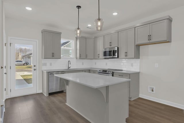 kitchen featuring sink, a center island, hanging light fixtures, dark hardwood / wood-style floors, and stainless steel appliances