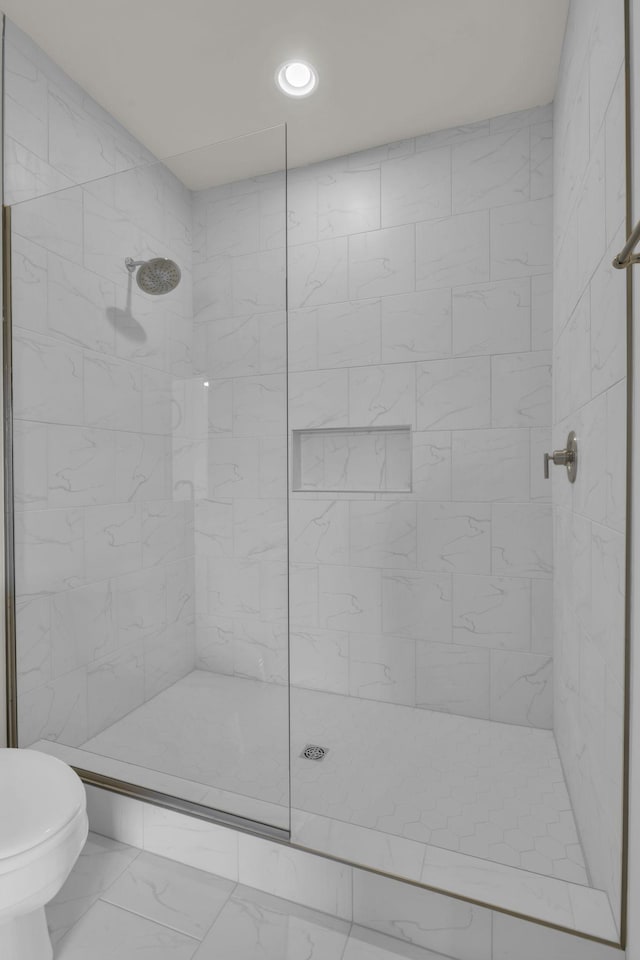 bathroom featuring toilet and a tile shower