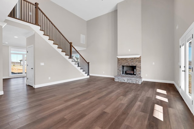 unfurnished living room featuring dark hardwood / wood-style floors, a fireplace, and a towering ceiling