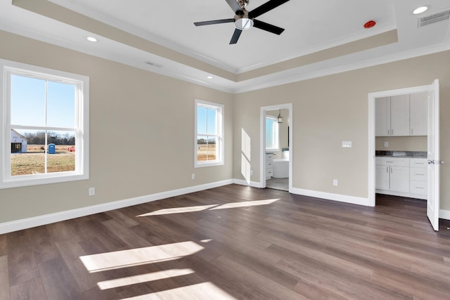 interior space featuring crown molding, ceiling fan, dark hardwood / wood-style floors, ensuite bathroom, and a tray ceiling