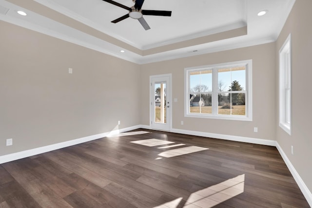 empty room with ornamental molding, dark hardwood / wood-style flooring, and a tray ceiling