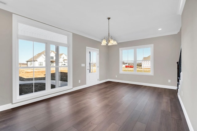 empty room featuring crown molding, dark wood-type flooring, and an inviting chandelier