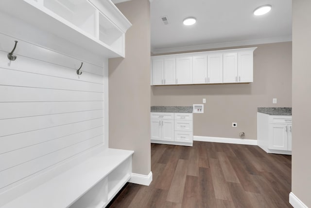 mudroom with crown molding, built in desk, and dark hardwood / wood-style flooring