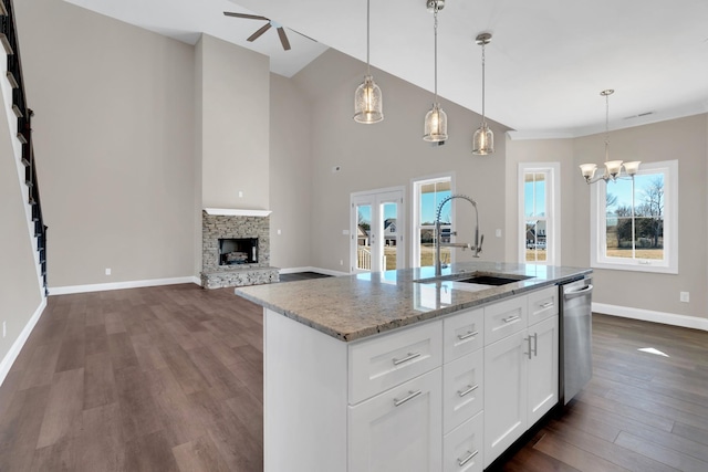 kitchen featuring white cabinetry, decorative light fixtures, a kitchen island with sink, and sink