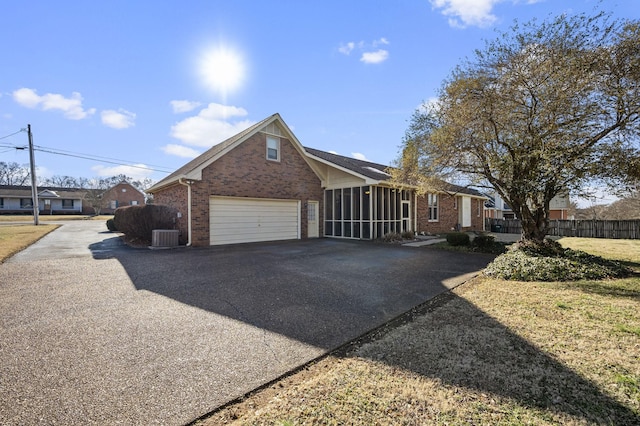 view of front of property featuring a garage, a sunroom, and central air condition unit