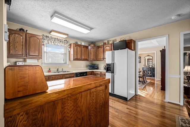 kitchen with a textured ceiling, dishwasher, kitchen peninsula, white refrigerator with ice dispenser, and hardwood / wood-style floors