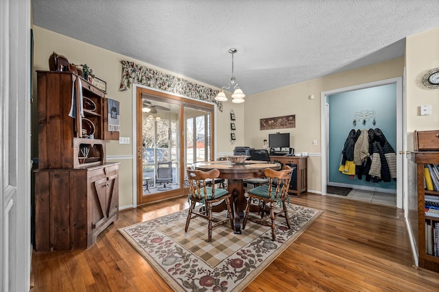 dining area featuring an inviting chandelier, wood-type flooring, and a textured ceiling