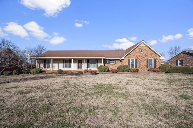 ranch-style home featuring covered porch and a front lawn