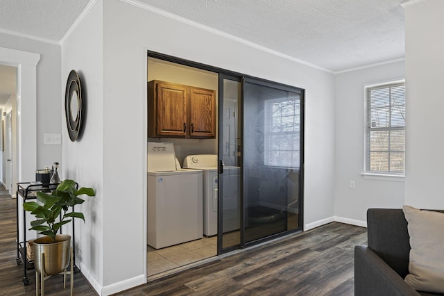 laundry room with hardwood / wood-style floors, washing machine and dryer, cabinets, ornamental molding, and a textured ceiling