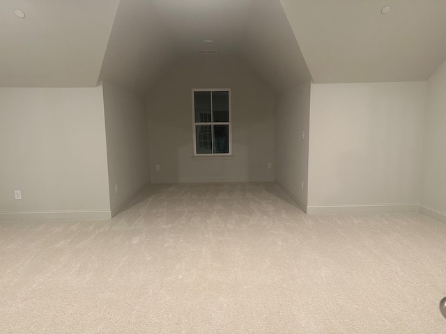 additional living space featuring lofted ceiling and light carpet