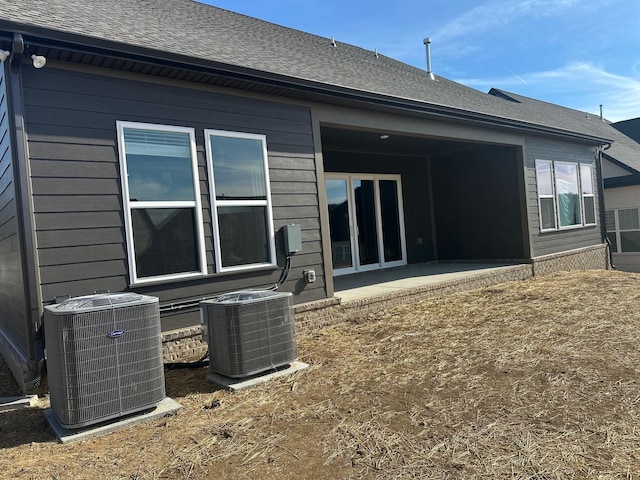 back of property with central AC unit and a patio