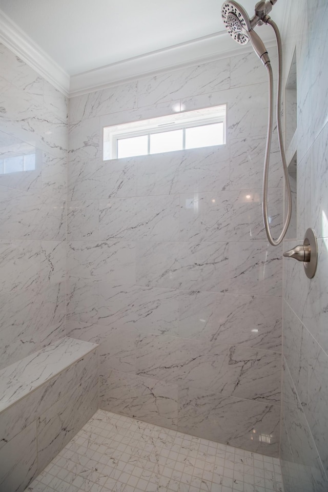 bathroom with ornamental molding and a tile shower