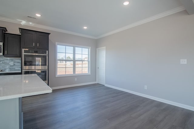 kitchen featuring light stone counters, ornamental molding, appliances with stainless steel finishes, and dark wood-type flooring