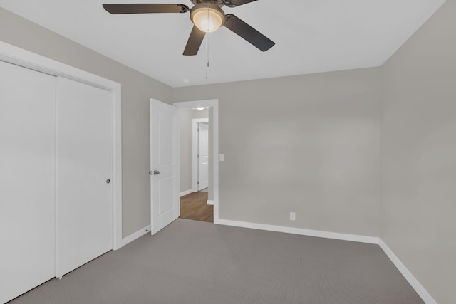 unfurnished bedroom with ceiling fan, carpet floors, a closet, and baseboards