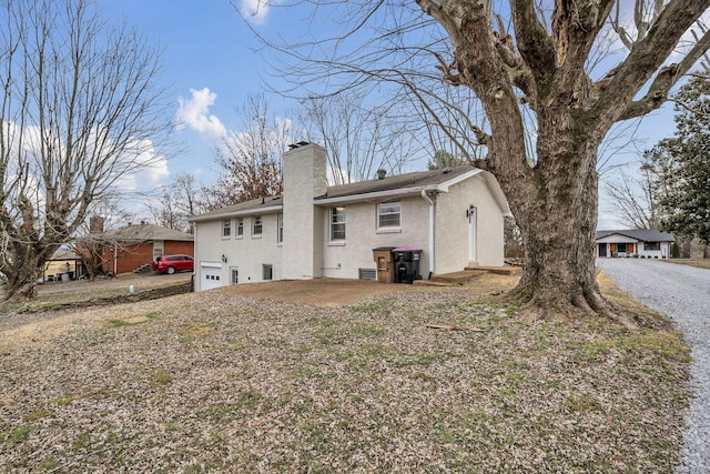 back of property featuring a garage, entry steps, a chimney, and brick siding