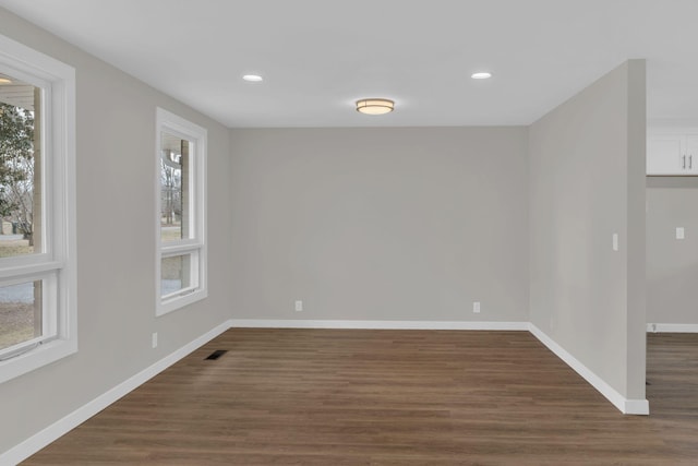 spare room featuring dark wood-type flooring, recessed lighting, visible vents, and baseboards