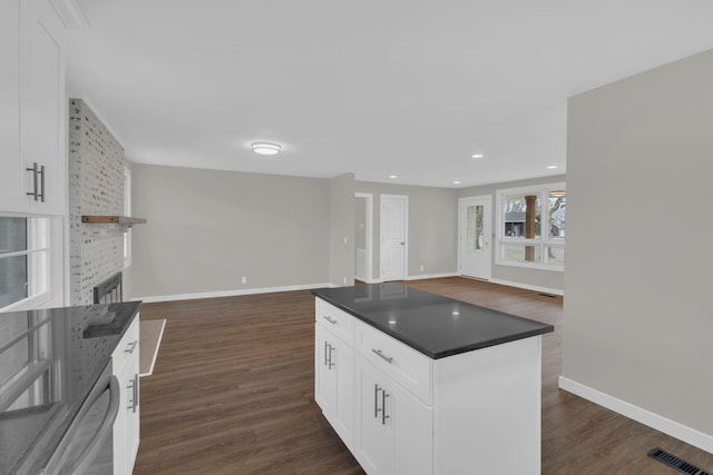 kitchen featuring open floor plan, dark wood-type flooring, dark countertops, and a fireplace