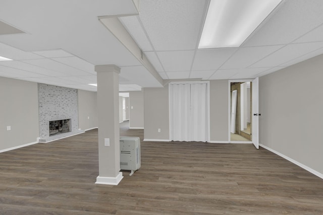 finished basement featuring a drop ceiling, a fireplace, and wood finished floors