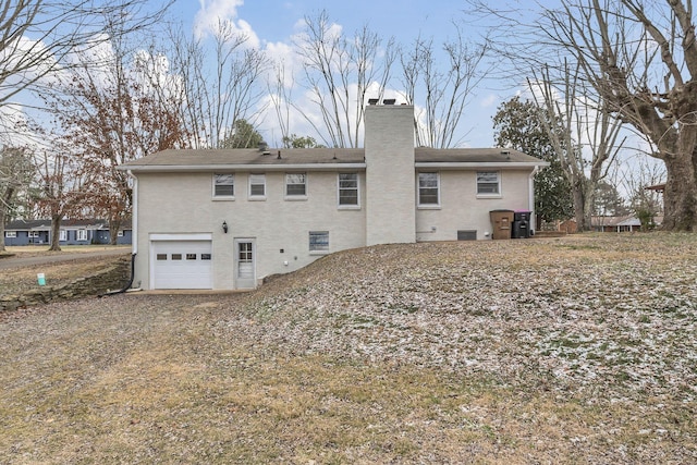 back of house with an attached garage, crawl space, a chimney, and brick siding