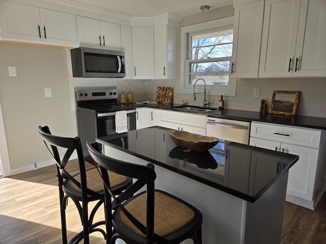 kitchen with appliances with stainless steel finishes, dark countertops, a sink, and decorative backsplash