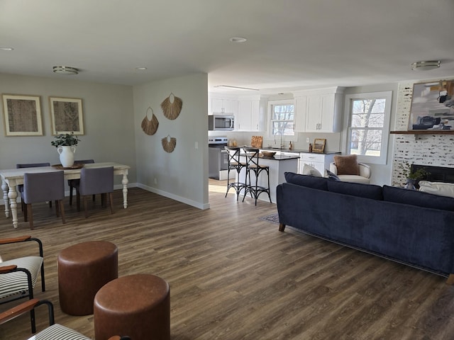 living room featuring dark wood-style floors, a fireplace, and baseboards