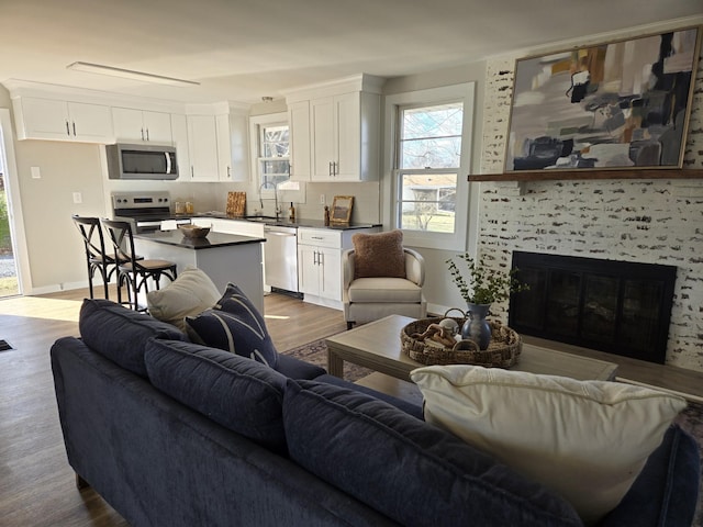 living area with a tiled fireplace, wood finished floors, and baseboards