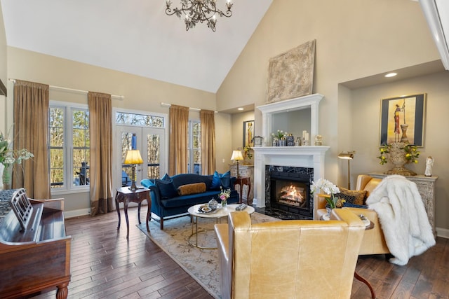 living room with high vaulted ceiling, dark wood-type flooring, a chandelier, and a fireplace