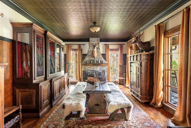 dining area featuring hardwood / wood-style flooring, ornamental molding, a fireplace, and plenty of natural light