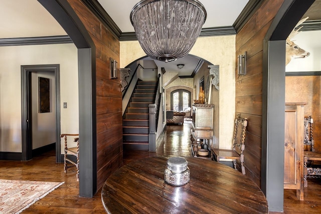 hallway featuring crown molding, dark wood-type flooring, a notable chandelier, and wood walls