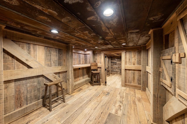 basement featuring light hardwood / wood-style floors and wood walls