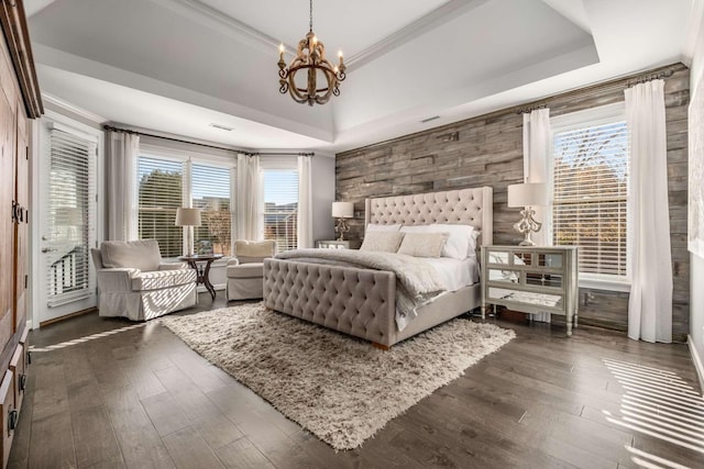 bedroom with dark wood-style floors, a notable chandelier, crown molding, and a raised ceiling