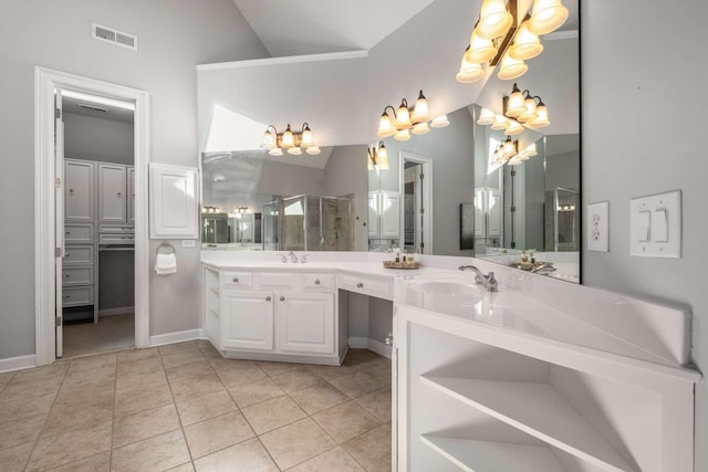 bathroom featuring vanity, a shower with door, tile patterned flooring, and vaulted ceiling