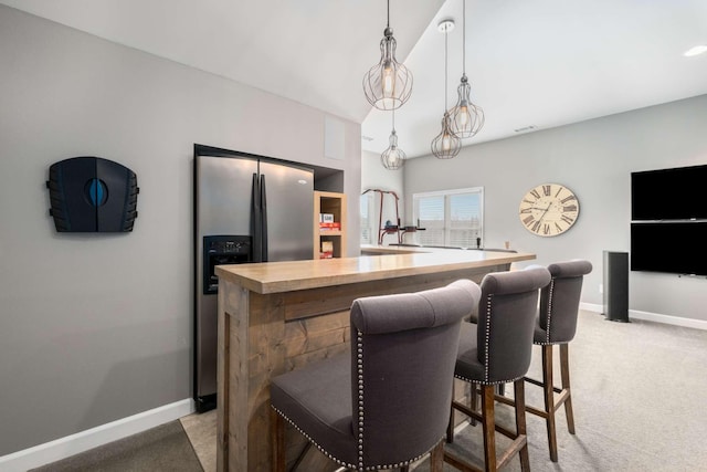 kitchen featuring a center island, baseboards, stainless steel fridge with ice dispenser, light carpet, and hanging light fixtures